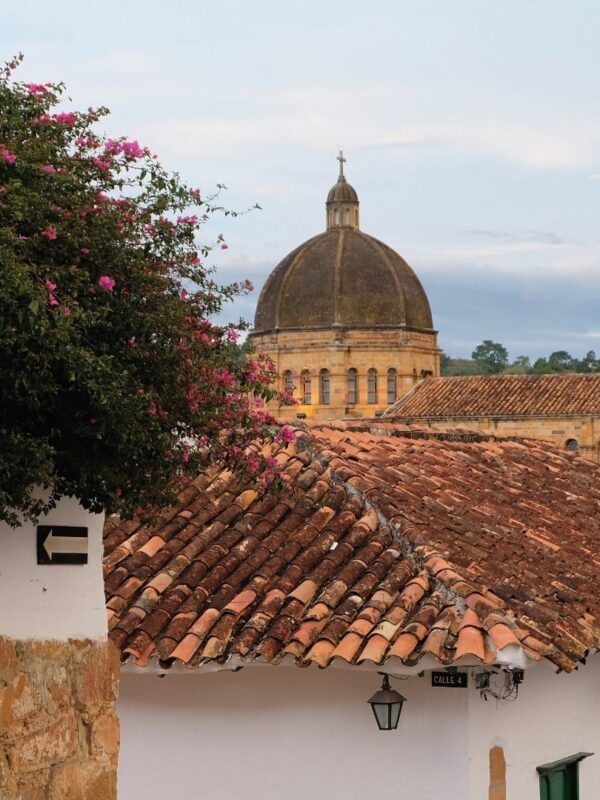 Vista de una calle empedrada de Barichara con fachadas blancas y balcones de madera, Colombia.