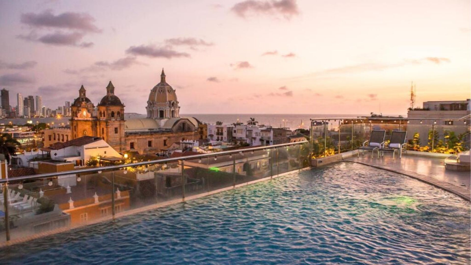 Piscina infinita con vista al atardecer de Cartagena y la torre de San Pedro Claver, lujo caribeño y elegancia histórica.