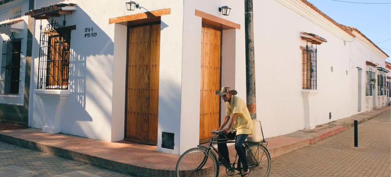 Hombre en bicicleta antigua por calles coloniales de Mompox, lujo artesanal e historia viva del Caribe colombiano.