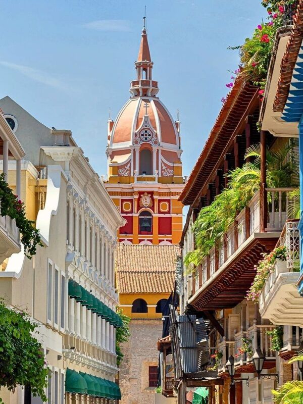 Vista panorámica de la arquitectura colonial de Cartagena de Indias con fachadas coloridas y balcones florecidos bajo la luz del sol caribeño.