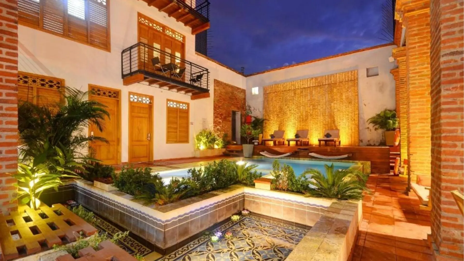 Patio colonial con piscina iluminada al anochecer en un hotel boutique de Santa Marta