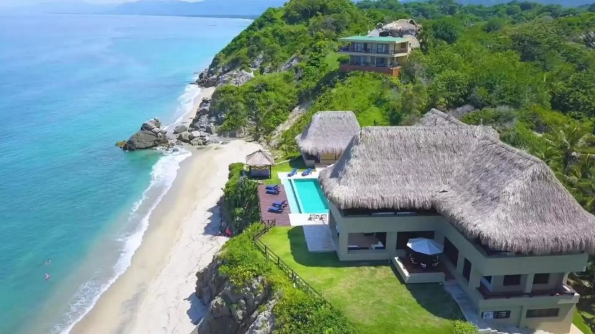 Vista aérea de un hotel boutique con techos de palma frente al mar Caribe, cerca del Parque Tayrona